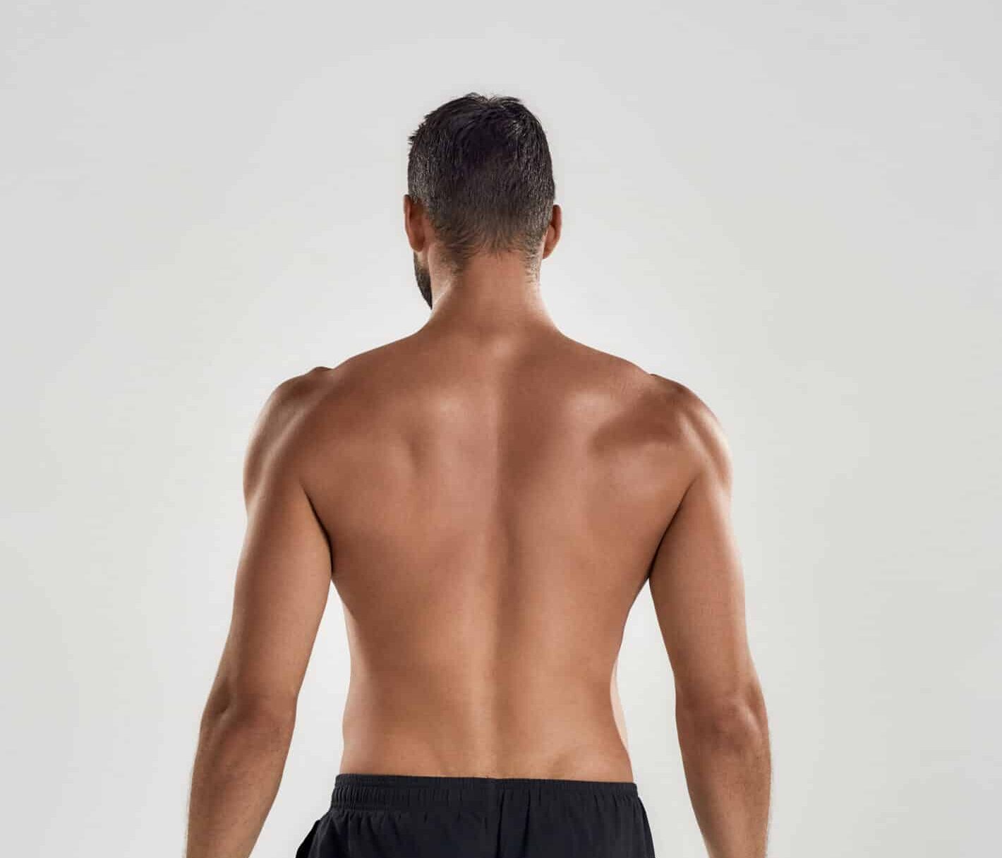 A man turned around, showcasing the toned appearance of his back and lower torso.