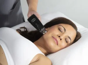 A woman receiving radiofrequency microneedling treatment on her jaw with the Morpheus8 hand piece.