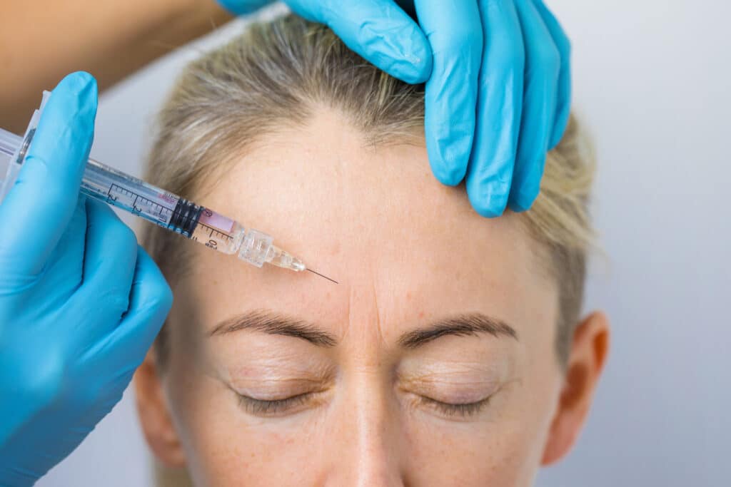 A woman receiving neurotoxin injection to reduce forehead lines.